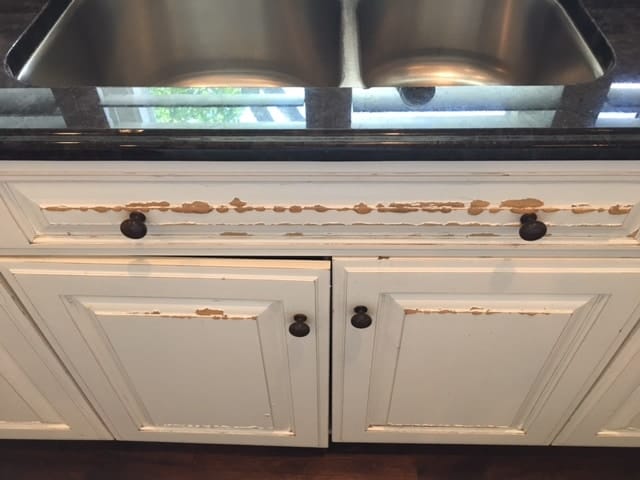Peeling cabinet paint under kitchen sink from moisture exposure